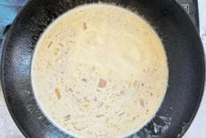 creamy white sauce with shallots in a cast iron skillet.