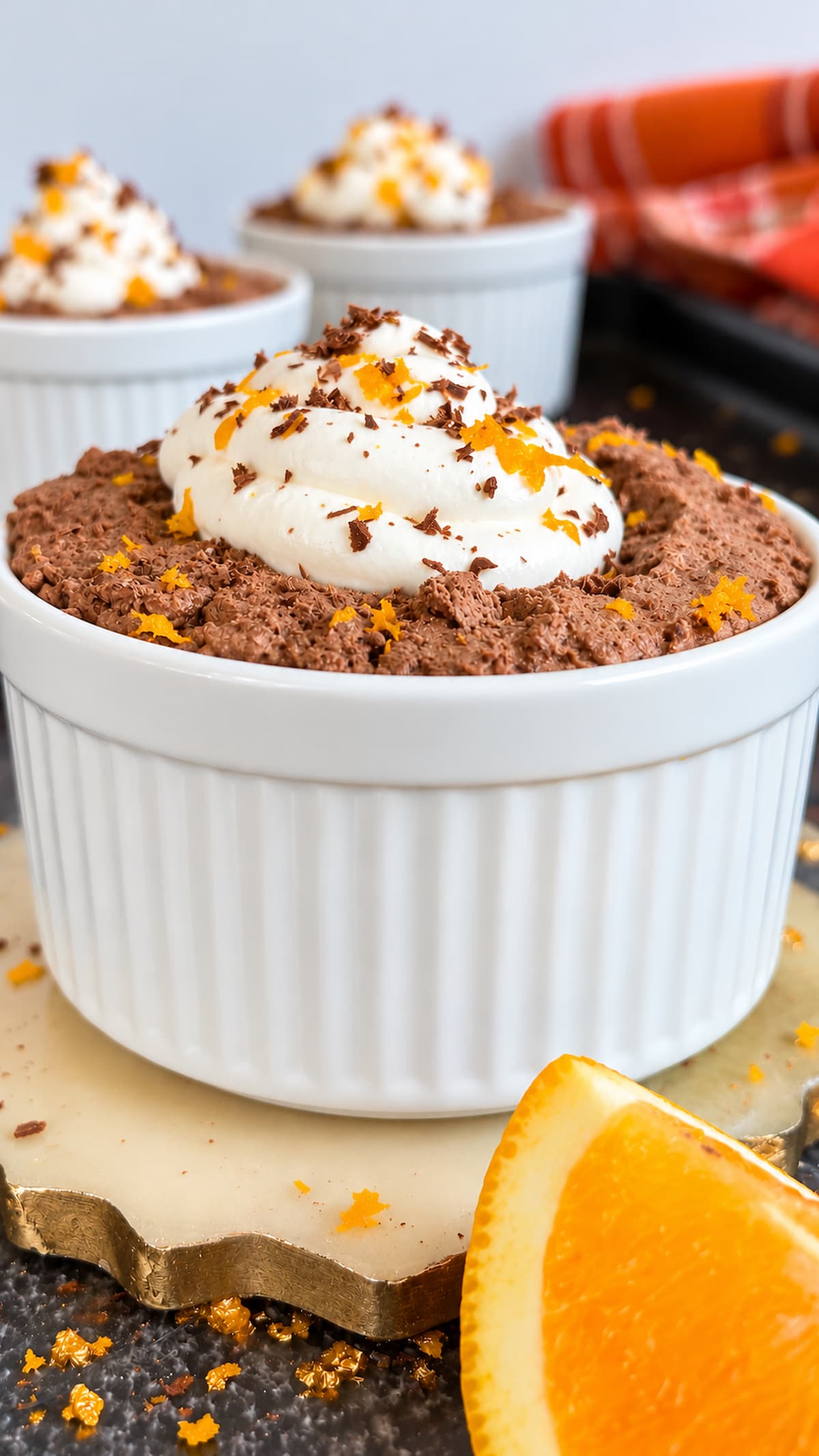 Chocolate orange mousse topped with whipped cream, orange zest, and chocolate shavings in a white ramekin.