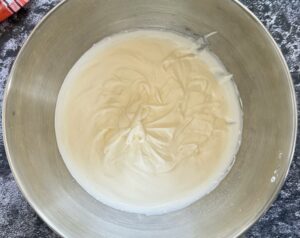 whipped cream with stiff peaks in a large silver bowl.