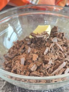 bowl of chopped chocolate with a pat of butter on top.