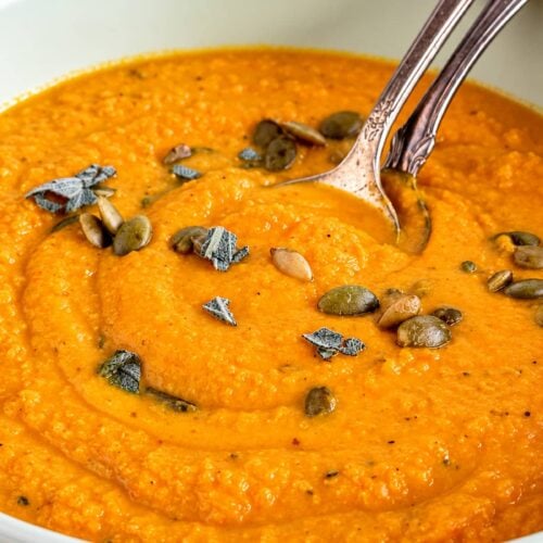 Creamy sweet potato pumpkin soup topped with pumpkin seeds and fresh sage.