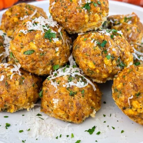 Pumpkin meatballs topped with grated Parmesan and fresh parsley on a white serving plate.