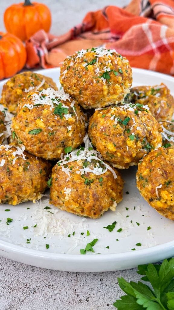 Pumpkin meatballs topped with grated Parmesan and fresh parsley on a white serving plate.