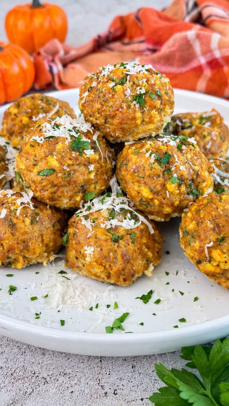 Pumpkin meatballs topped with grated Parmesan and fresh parsley on a white serving plate.