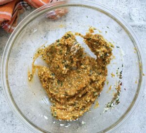 mixture for pumpkin meatballs with pumpkin puree, panko, spices, and herbs in a glass bowl.
