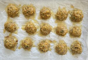 15 baked turkey pumpkin meatballs on a piece of parchment paper.