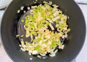 diced celery and onions cooking in a large black pot.