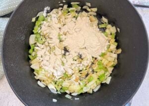 diced onions and celery topped with flour in a large black pot.