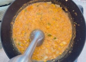 immersion blender in a pot of shrimp and corn bisque.