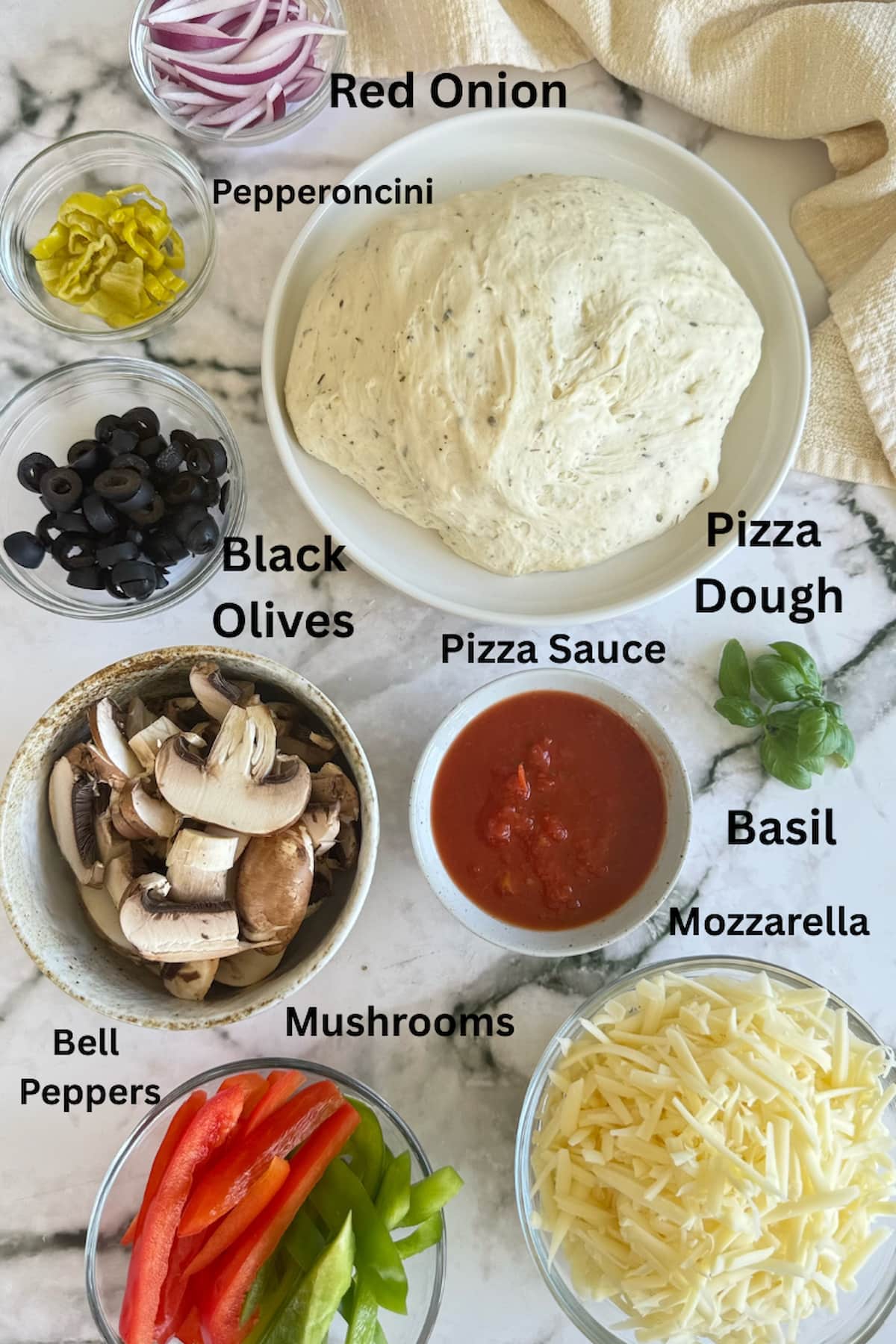 ingredients for veggie supreme pizza - pizza dough, pizza sauce, mushrooms, red onion, pepperoncini, black olives, bell pepper, basil, and mozzarella.