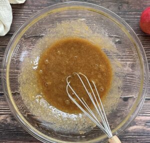 brown liquid in a large glass bowl with a whisk.