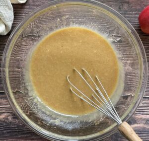 light beige batter in a glass bowl with a whisk.
