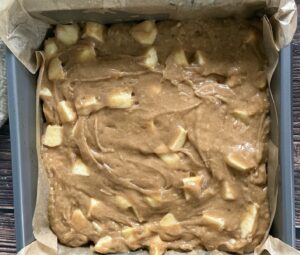 unbaked apple spice cake in a parchment lined square baking pan.