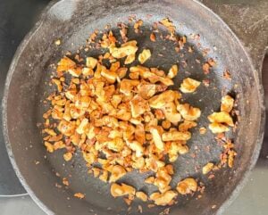 chopped walnuts cooking in a cast iron skillet.