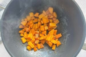cubed and seasoned butternut squash cooking in a wok.