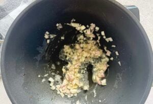 minced shallots cooking in butter and olive oil in a wok.