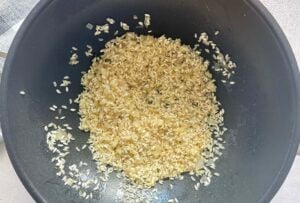 arborio rice and minced shallots cooking in a wok.