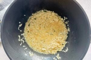 arborio rice cooking in broth in a wok with fresh parsley.