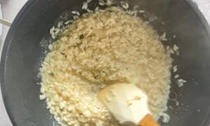 risotto being stirred in a wok with a rubber spatula.