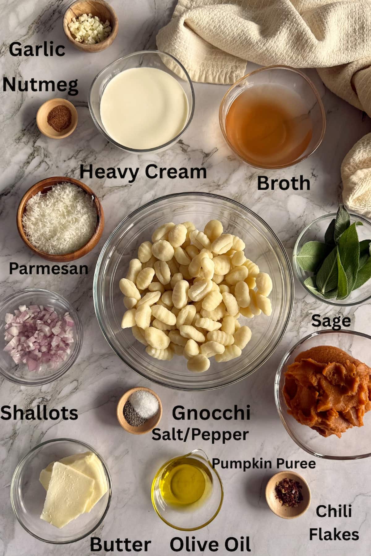 ingredients for gnocchi in pumpkin sauce - pumpkin puree, garlic, nutmeg, heavy cream, gnocchi, broth, parmesan, sage, shallots, butter, olive oil, chili flakes, salt, and pepper.