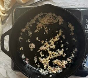 minced garlic and shallots cooking in butter in a cast iron skillet.