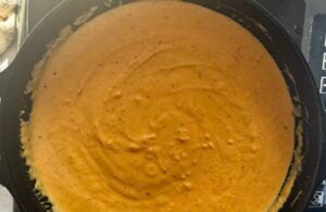 creamy pumpkin sauce for gnocchi cooking in a cast iron skillet.
