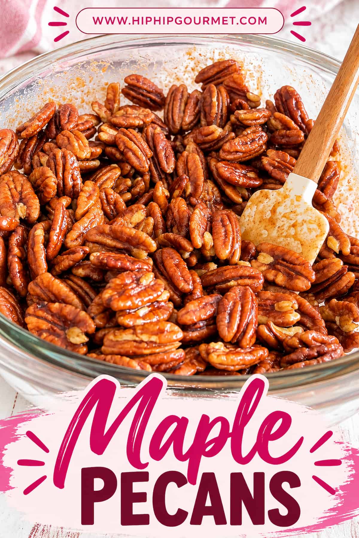 Maple pecans coated in a glossy, sweet maple glaze in a glass mixing bowl with a wooden spatula. Pinterest pin features “Maple Pecans” in bold pink and berry lettering at the bottom and www.hiphipgourmet.com at the top.