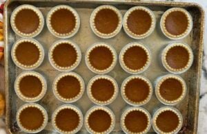 baked pumpkin pie tarts laid out in a single layer on a baking sheet.