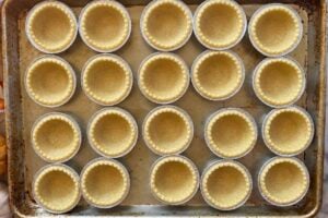 empty pie tart shells in a single layer on a baking sheet.